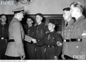 Przywódca młodzieży Rzeszy Artur Axmann (z lewej) wręcza kilku członkom Hitlerjugend Wojenny Krzyż Zasługi z Mieczami, zaś szesnastoletniemu Nikolausowi Willms (trzeci z prawej) Krzyż Żelazny II klasy, październik 1942 r